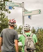 Foto mit zwei Radfahrern an einer Radwegebeschilderung